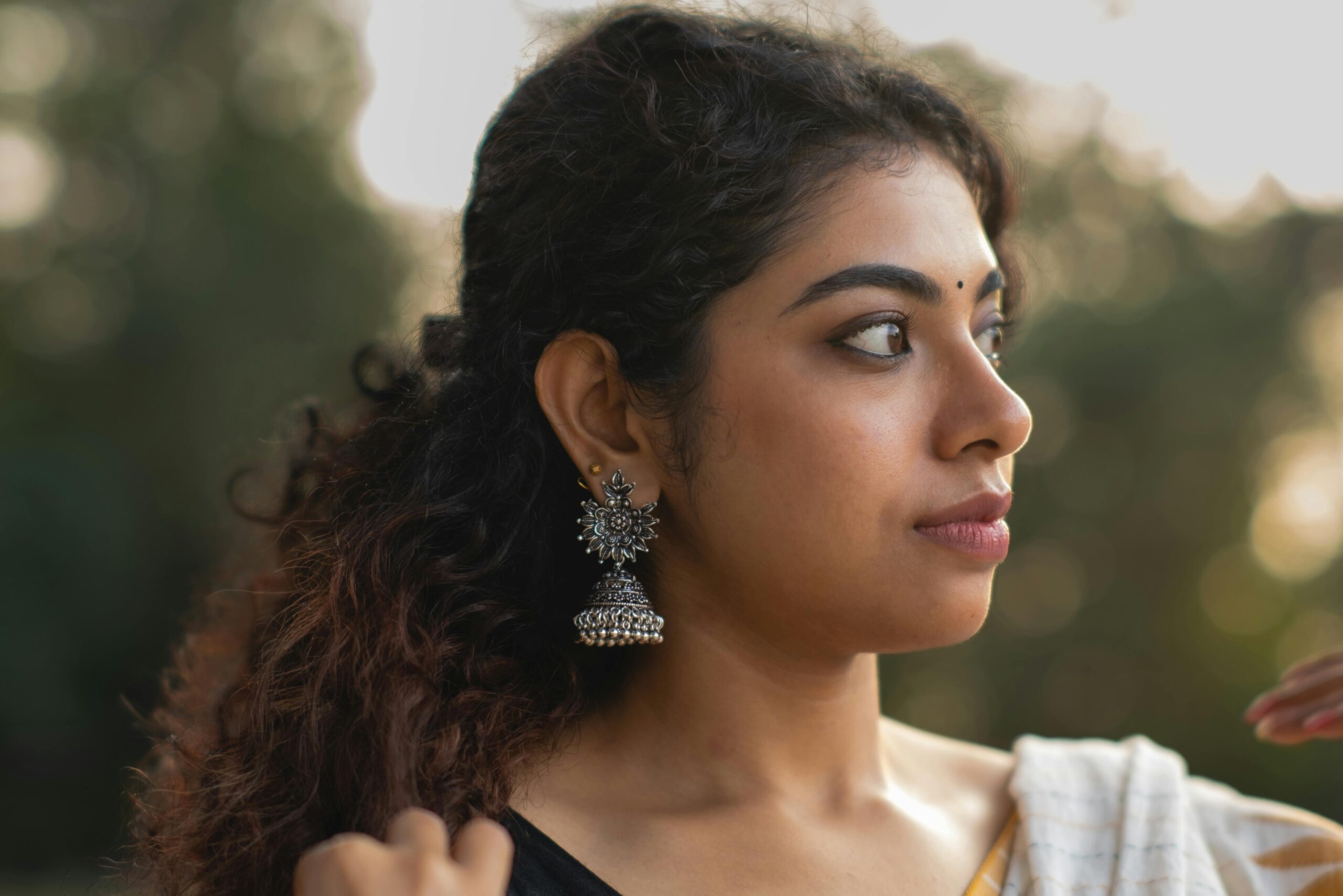 Profile of a woman with silver earrings outdoors, exuding elegance and style.